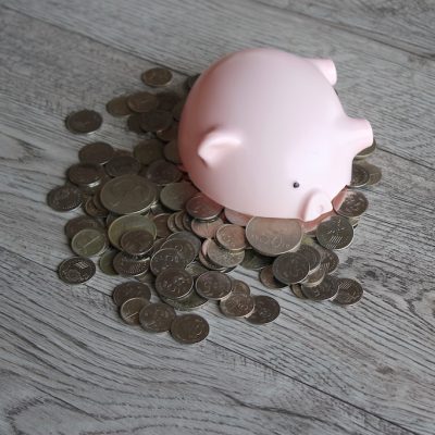Broken piggy bank and coins on wooden table with copy space. Financial concept.