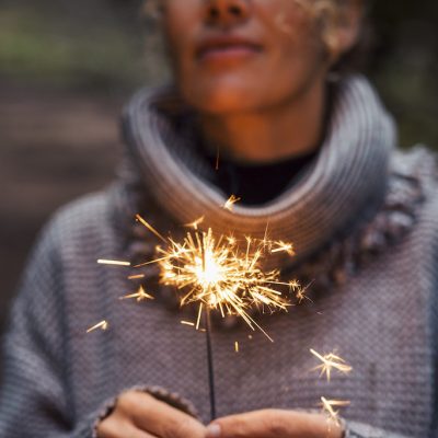 Close up of woman people holding sparkler and celebrate outdoor. New year eve and christmas celebration concept. Happiness and serene female person. Hope and future. One lady celebration. Fireworks