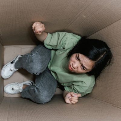 a fearful woman having claustrophobia in a cardboard box