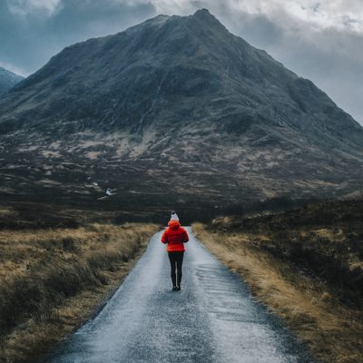 Woman walking on a road in Glen Etive, Scotland